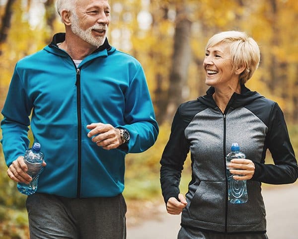 An elderly couple on a morning run with water bottles in their hands in Ann Arbor, MI